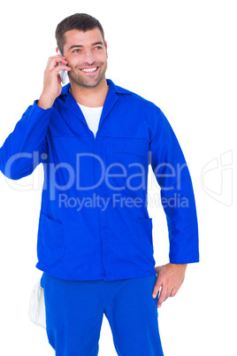 Smiling male mechanic using mobile phone