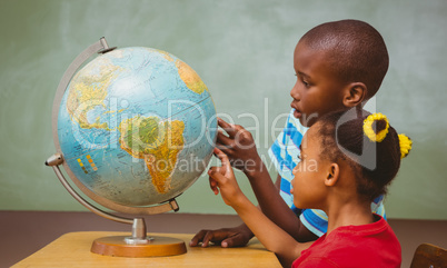 Kids pointing at globe in classroom