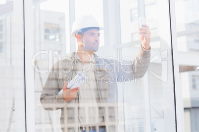 Architect with blueprints photographing through mobile phone in Architect with blueprints photographing through mobile phone in