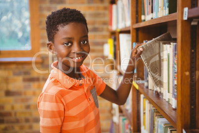 Portrait of boy selecting book in library