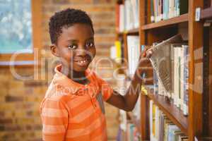 Portrait of boy selecting book in library