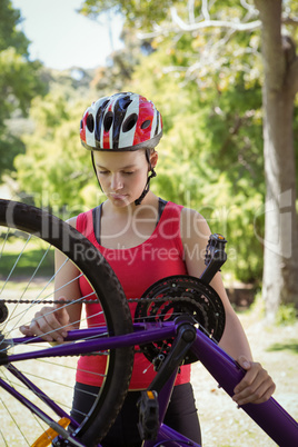 Fit woman fixing the chain on her bike