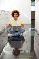 Smiling young man using laptop on floor