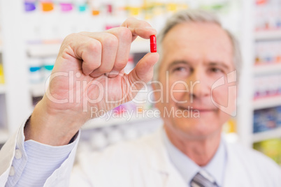 Smiling pharmacist in lab coat showing pill