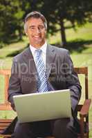 Businessman using laptop in the park