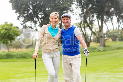 Golfing couple smiling at camera on the putting green