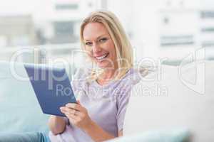 Woman using tablet computer on sofa at home