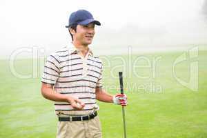 Cheerful golfer holding his club and golf ball
