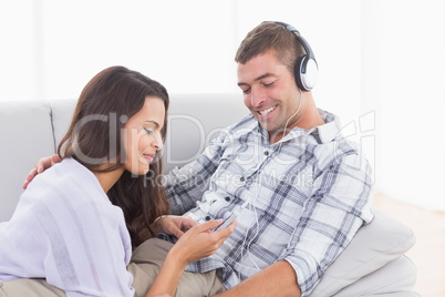 Woman playing music for man on mobile phone