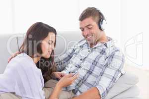 Woman playing music for man on mobile phone