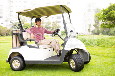 Golfer driving his golf buggy looking at camera