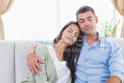 Couple with eyes closed sitting on sofa