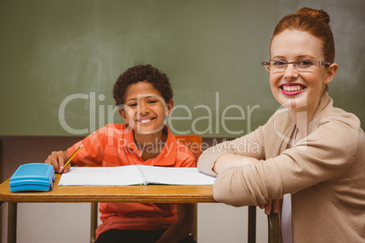 Teacher assisting little boy with homework in classroom