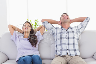 Couple with hands behind head sitting on sofa