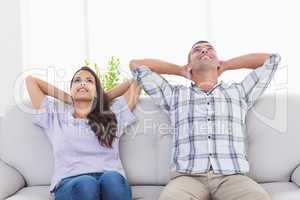 Couple with hands behind head sitting on sofa