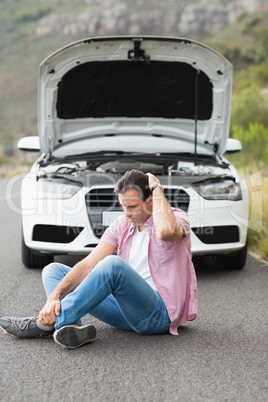 Stressed man sitting after a car breakdown