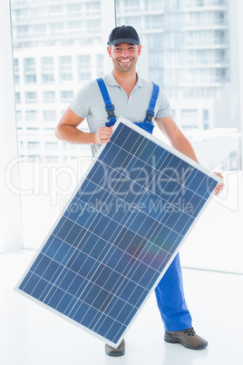 Manual worker holding solar panel in bright office