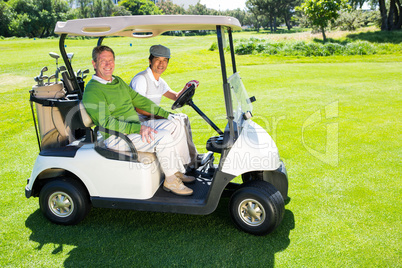 Golfing friends driving in their golf buggy smiling at camera