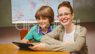 Teacher and boy using digital tablet in classroom