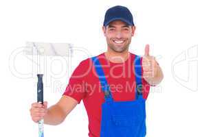 Smiling handyman with paint roller gesturing thumbs up