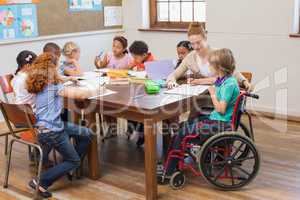 Pretty teacher helping pupils in classroom