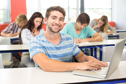 Male student using laptop in classroom