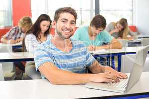 Male student using laptop in classroom