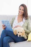 Woman with dog using tablet computer on sofa