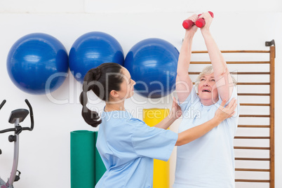 Therapist helping senior woman fit dumbbells