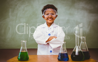 Cute boy with conical flasks in classroom