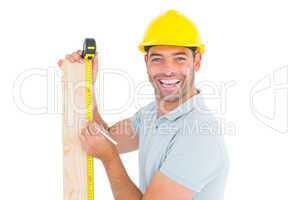 Construction worker using measure tape to mark on plank