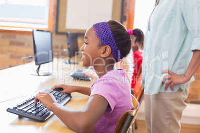 Cute pupil in computer class with teacher