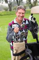 Happy golfer beside his golf buggy