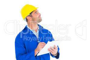 Male supervisor looking up while writing on clipboard