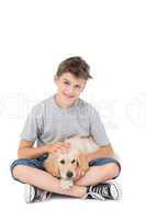 Boy stroking dog while sitting over white background