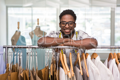 Male fashion designer leaning on rack of clothes