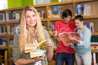 Female college student holding books in library