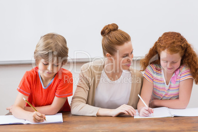 Teacher and pupils working at desk together