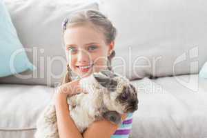 Happy girl holding rabbit in living room