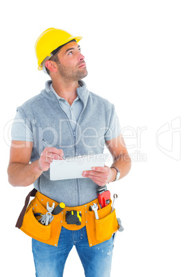 Manual worker looking away while writing on clipboard