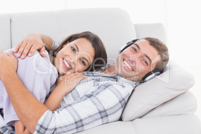 Happy man wearing headphones while embracing woman