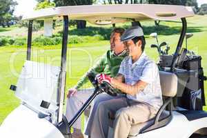 Golfing friends laughing together in their golf buggy