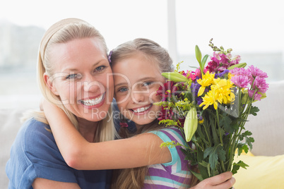 Mother with bouquet embracing daughter in house