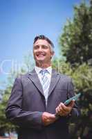 Businessman holding tablet in the park