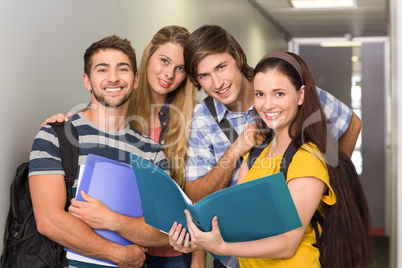 Students holding folders at college corridor