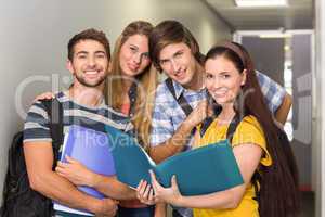 Students holding folders at college corridor