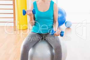 Woman exercising with dumbbells on fitness ball