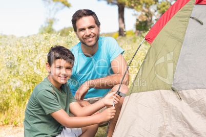 Father and son pitching their tent