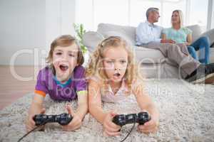 Siblings playing video game while parents sitting on sofa