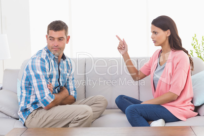 Woman pointing at man while sitting on sofa